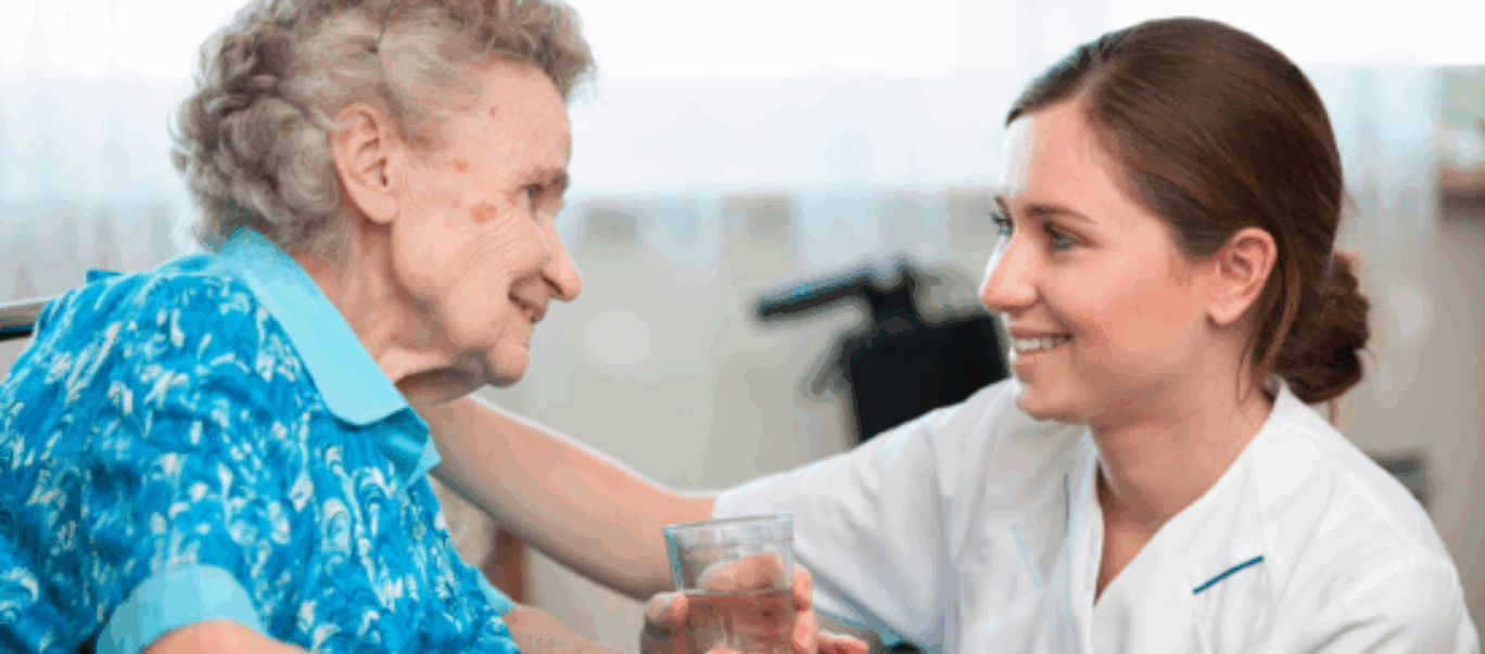 Nurse with arm round elderly patient with both of them smiling.