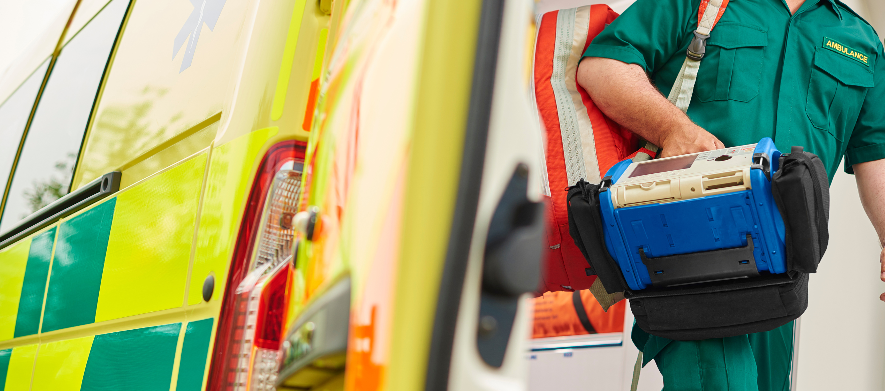 A male paramedic holding a defibrillator leaving an ambulance.