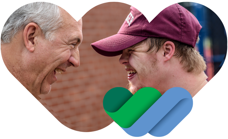 Image of a young man wearing a baseball cap smiling at an older man.