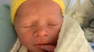 Image of newborn baby in hospital wearing a yellow knitted hat
