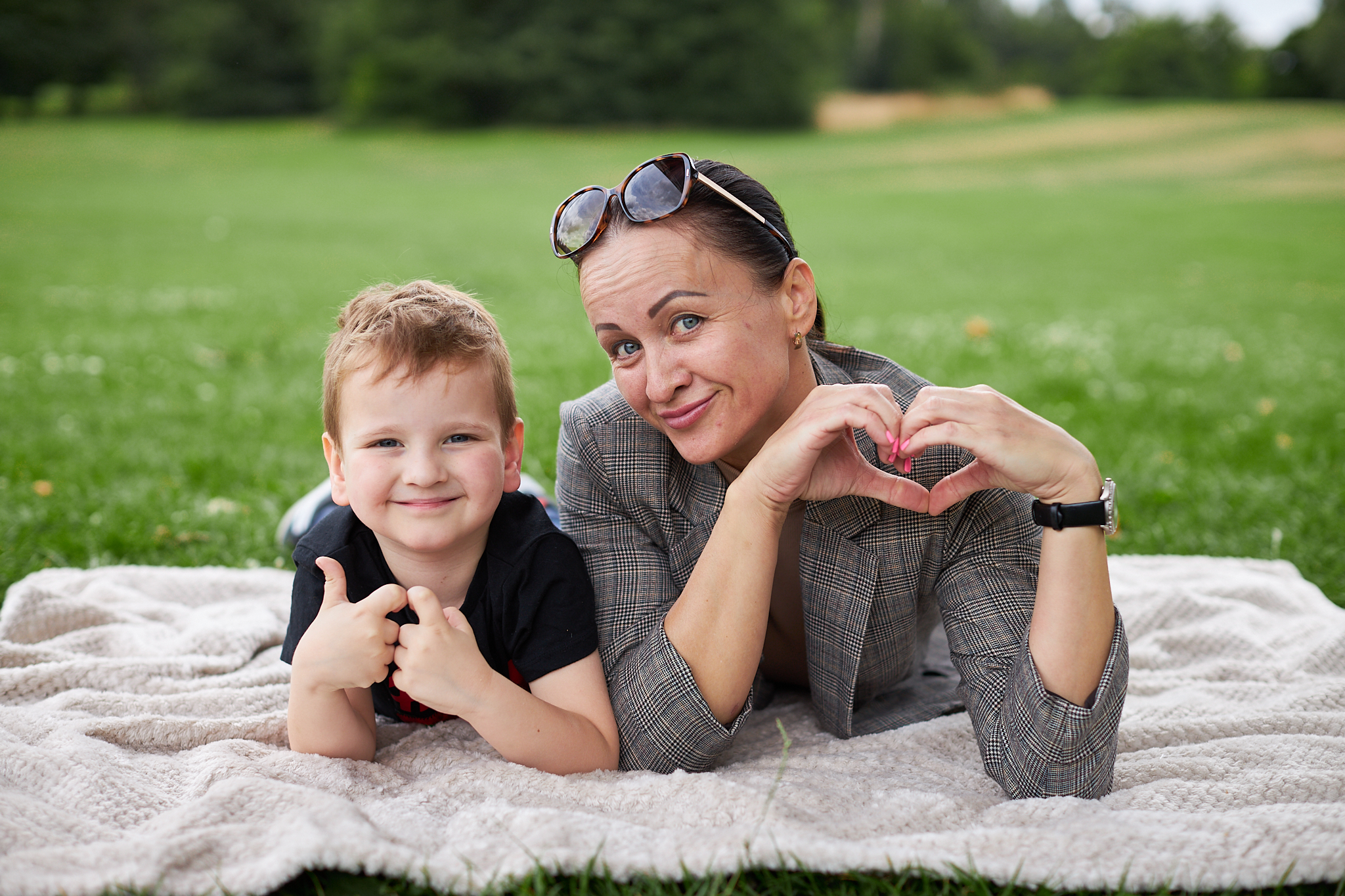 A mum and her son posing for a photo. The mum is creating a heart with her hands and her son has his thumbs up