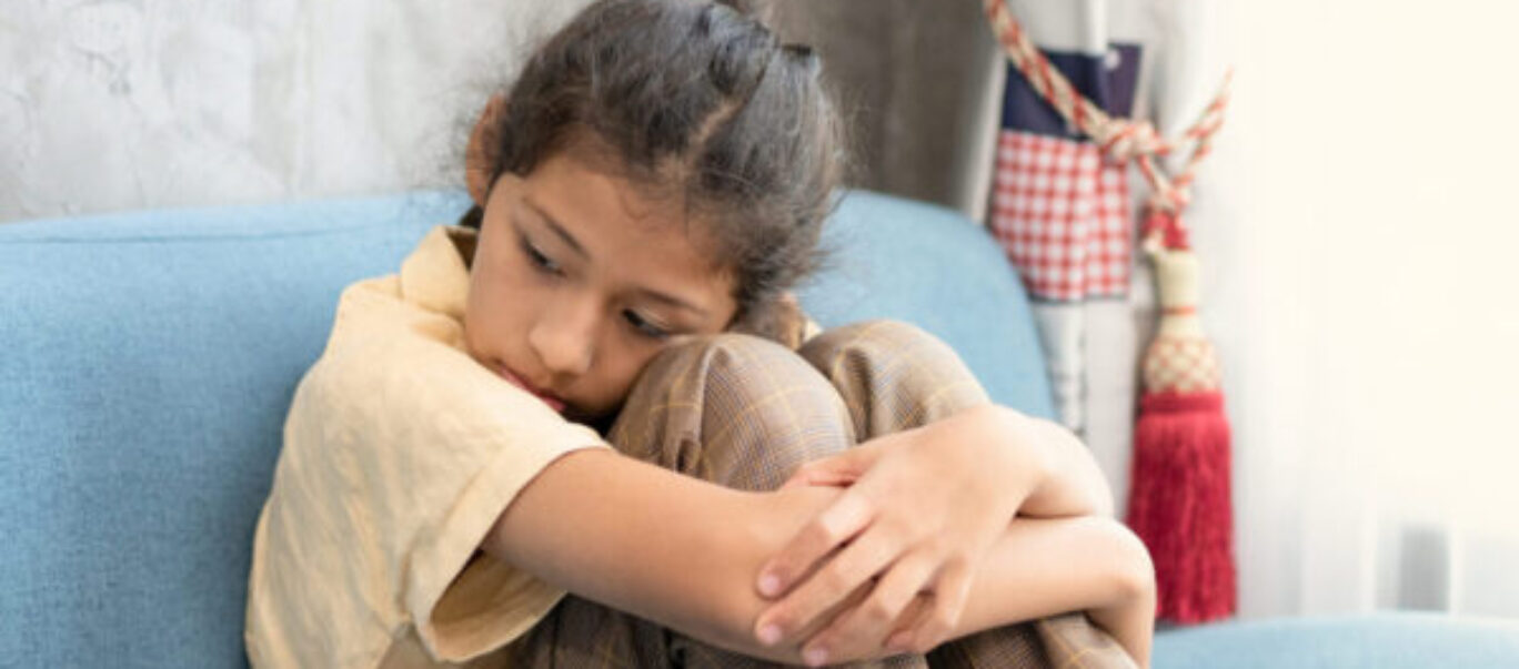 Girl looking sad with arms around her knees