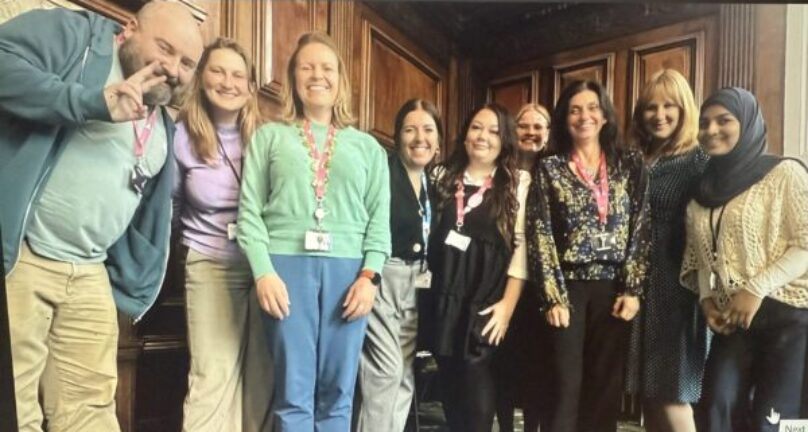 Group of people representing health inclusion organisations stood together and smiling.